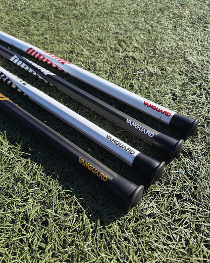 4 lacrosse sticks lying on grass with visible brand logos.
