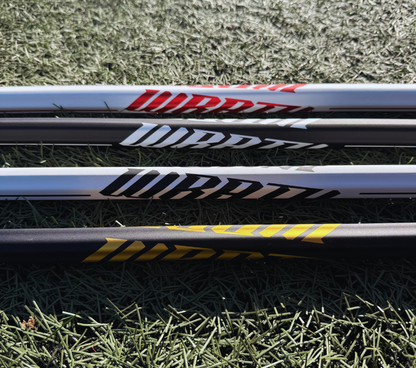 4 lacrosse sticks lying on grass with visible brand logos.