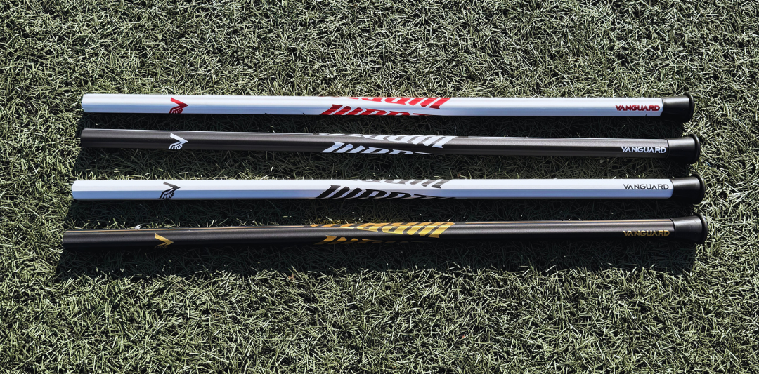 4 lacrosse sticks lying on grass with visible brand logos.
