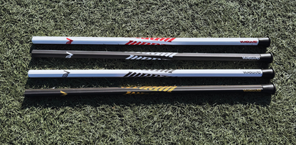 4 lacrosse sticks lying on grass with visible brand logos.