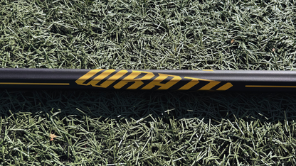 1 lacrosse stick lying on grass with visible brand logos.