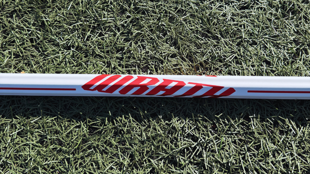 1 lacrosse stick lying on grass with visible brand logos.