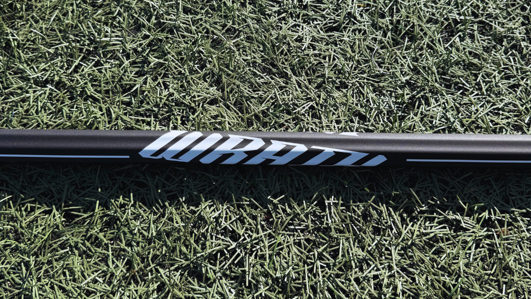 1 lacrosse stick lying on grass with visible brand logos.