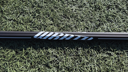 1 lacrosse stick lying on grass with visible brand logos.