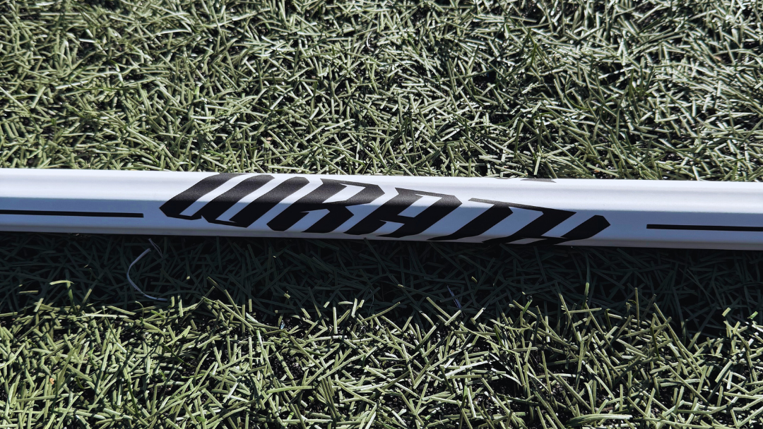 1 lacrosse stick lying on grass with visible brand logos.