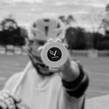 Person holding a lacrosse tape with a logo on it, outdoors.