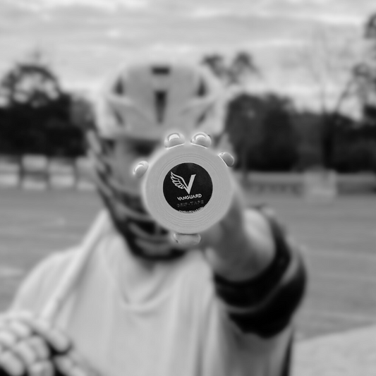 Person holding a lacrosse tape with a logo on it, outdoors.