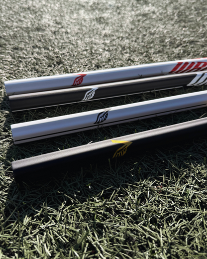 4 lacrosse sticks lying on grass with visible brand logos.