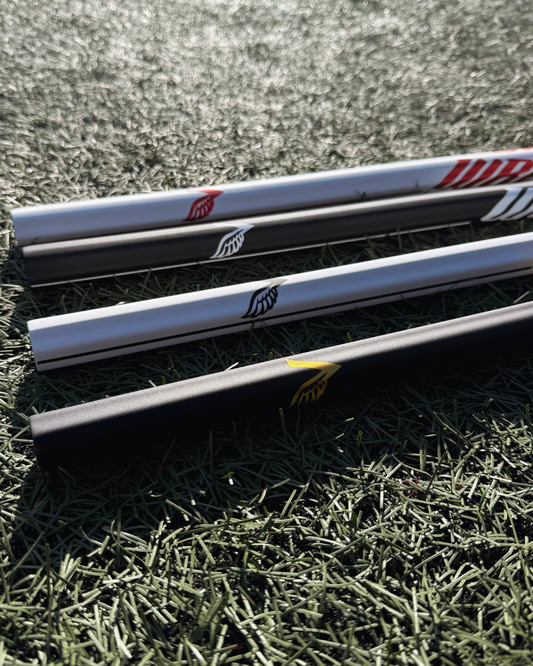 4 lacrosse sticks lying on grass with visible brand logos.